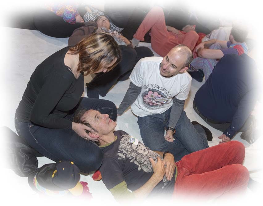 Workshop participants sit and lie on a studio floor, working closely together in pairs.